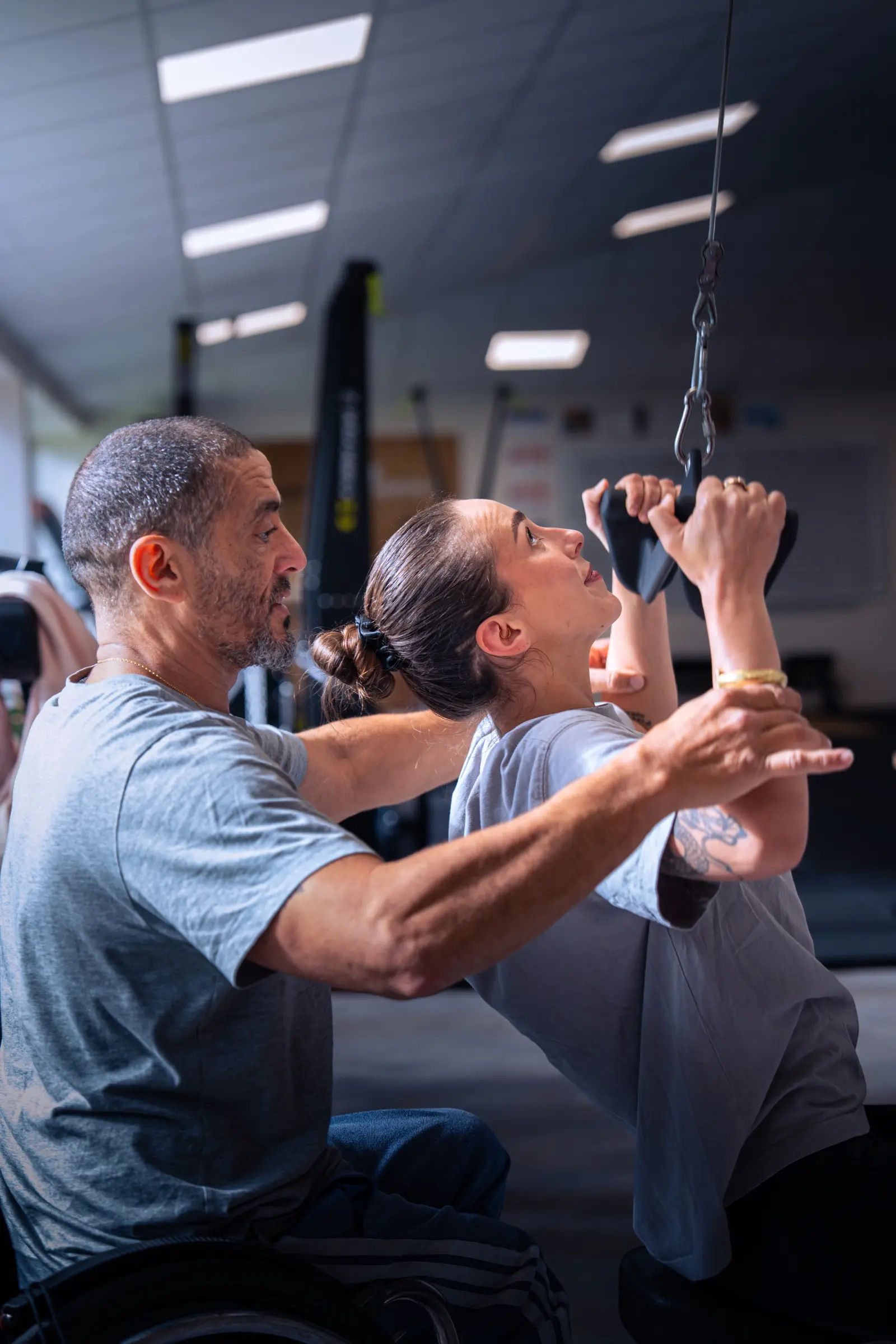 Coach corrigeant la posture d'une stagiaire à la barre de traction