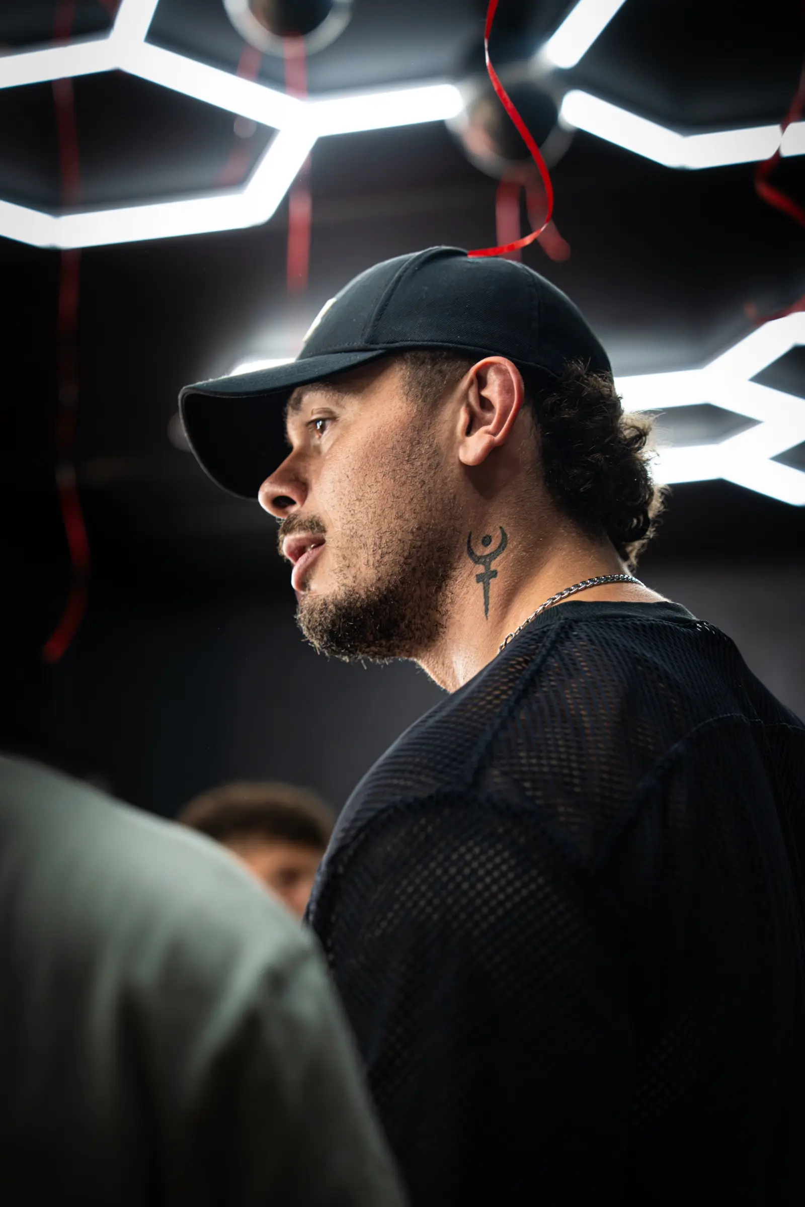 Portrait de profil d'un homme en casquette sous des néons hexagonaux